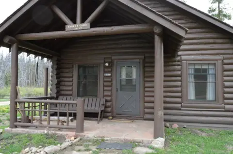 An exterior view of a brown log cabin with a porch.