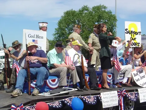 A group of veterans and a speaker on a decorated parade float.
