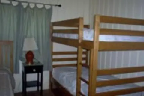 A bedroom featuring a wooden bunk bed and a nightstand with a lamp.