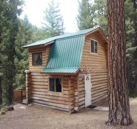 A two-story log cabin nestled in a forest.