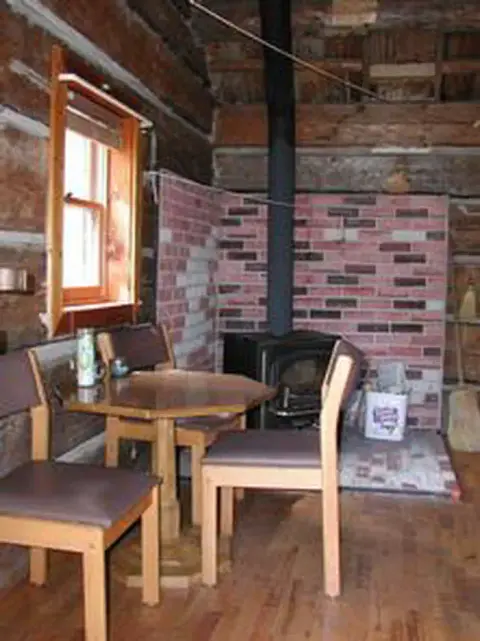 A view of the interior of a cabin with a table, chairs, and a stove.
