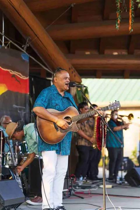A musician sings and plays guitar on stage with a band.