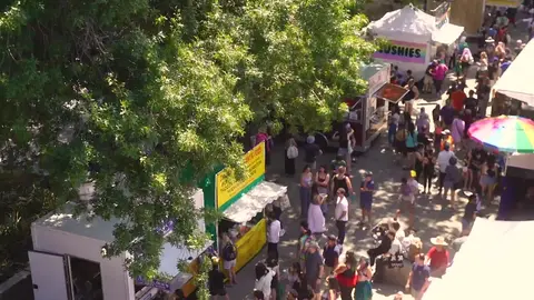 An elevated view of a bustling outdoor street fair with food booths and crowds.