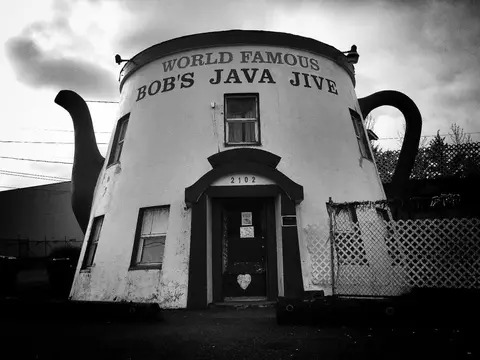 A black and white photograph of a building shaped like a teapot.