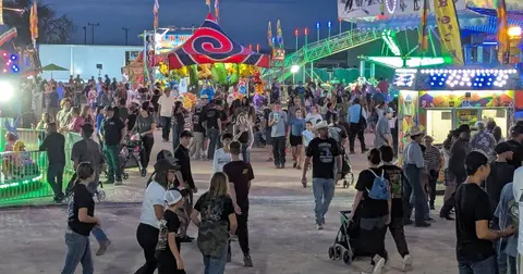 A crowd of people walking through a carnival at night.
