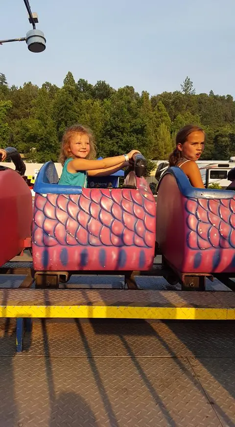 Two children riding a roller coaster at an amusement park.