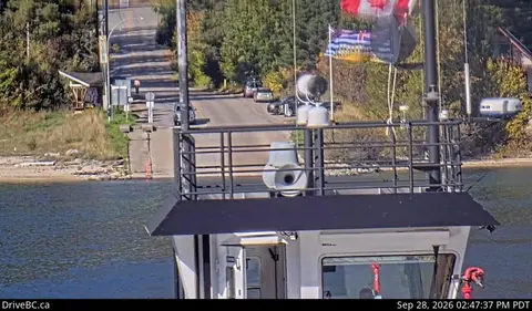 A view from a ferry approaching a boat ramp and road.