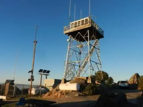A tall fire lookout tower stands under a clear blue sky.