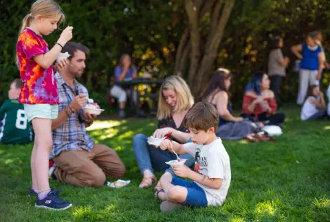 A family eating ice cream on the grass in a park.