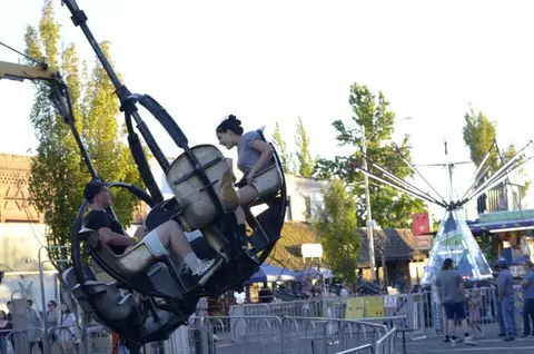 People riding a carnival ride at an outdoor fair.