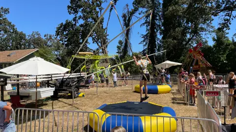 A child bounces on a bungee trampoline ride at an outdoor event.