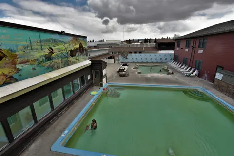 An outdoor hot springs pool area with a mural on the building side.