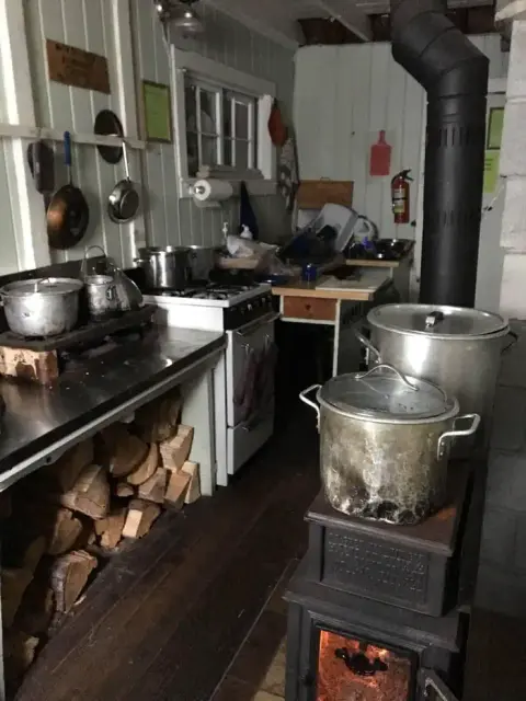 A rustic kitchen interior with a wood-burning stove and pots.
