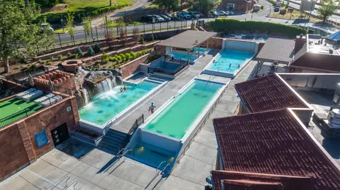 An aerial view of an outdoor hot springs resort with multiple pools and a waterfall.