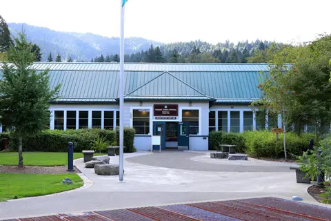 An exterior view of a hatchery building with a green roof and a flagpole in front.