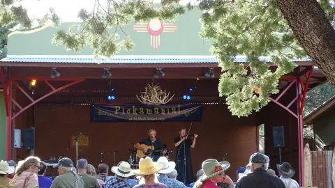 Musicians perform on an outdoor stage for an audience.