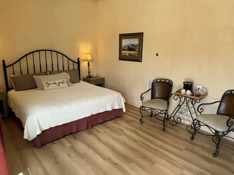 A cozy hotel room featuring a large bed, two chairs, and a small table with coffee supplies.