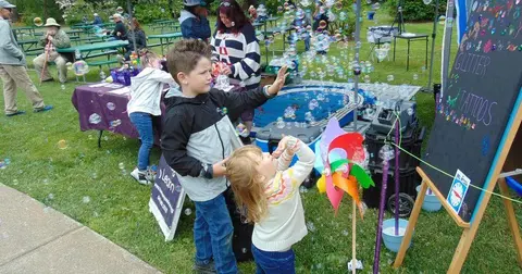 Children play with bubbles and toys outdoors on the grass.