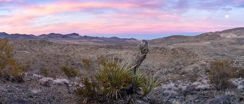 A panoramic view of a desert landscape under a colorful sunset sky.