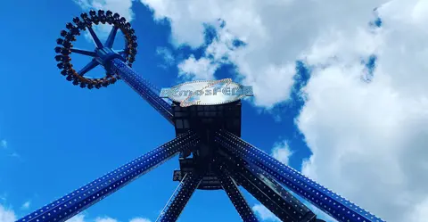 A low angle shot of an amusement park ride against a blue cloudy sky.