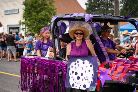 People ride in a decorated utility vehicle during an outdoor event.