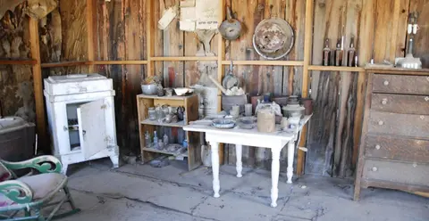 A rustic interior features vintage furniture and various household items.