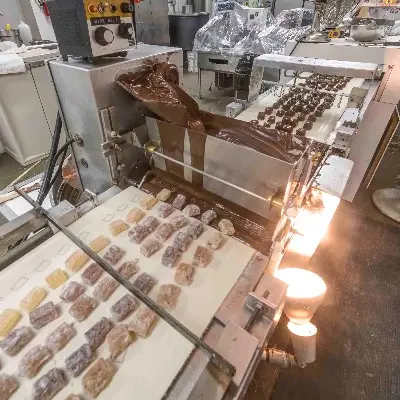 An industrial machine processes candy and chocolate on a production line.
