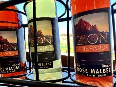 Three bottles of wine are arranged in a metal rack.