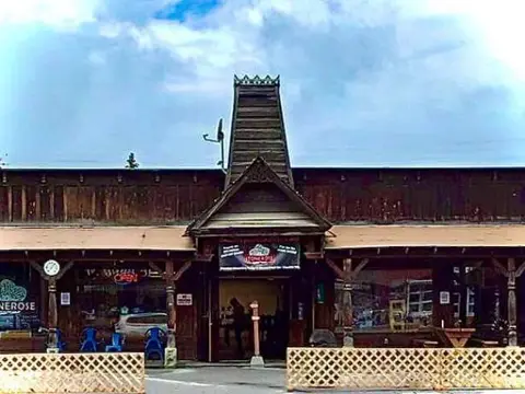 An exterior view of a rustic wooden building with a distinctive tall roof tower.