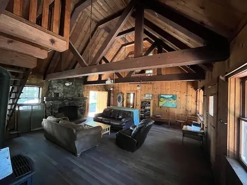 An interior view of a rustic wooden cabin living room with high vaulted ceilings and exposed beams.