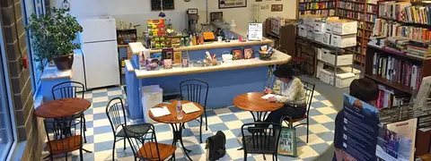An elevated interior view of a bookstore with a small cafe counter, tables, and bookshelves.