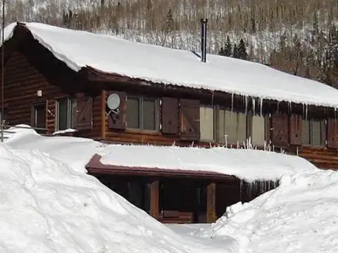 A log cabin covered in snow during winter.