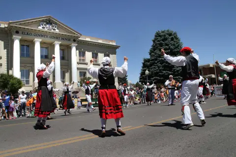 People in traditional costumes perform a street dance in front of a courthouse.