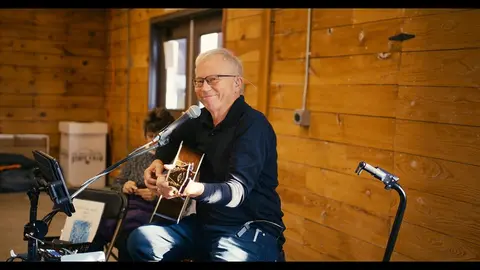A man plays a guitar indoors.