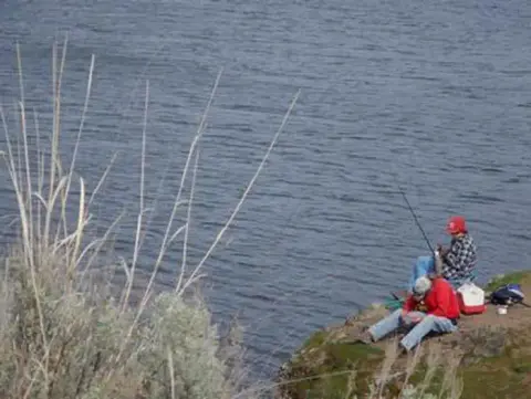 Two people fishing by a body of water.