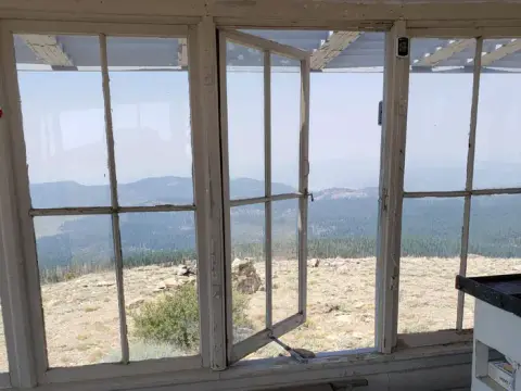 A view of a mountain landscape through the open windows of a lookout tower.