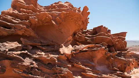 A close-up view of weathered red rock formations under a clear blue sky.