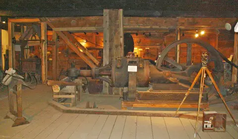 A large historic industrial engine displayed inside a wooden building.