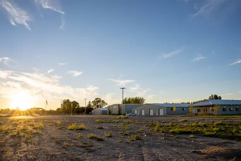A row of metal buildings under a bright sunset sky.