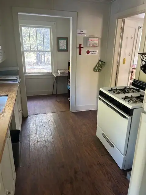 An interior view of a rustic kitchen with a stove and wooden floor.