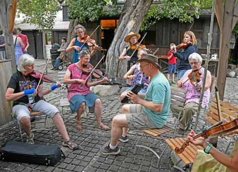 A group of people playing violins outdoors in a courtyard.
