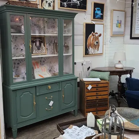 A green hutch and other furniture pieces displayed inside a shop.