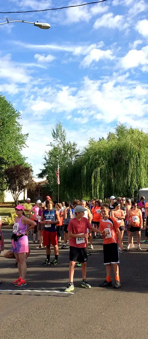 A crowd of participants gathered outdoors for a running event under a blue sky.