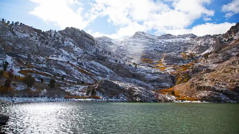 A scenic view of a lake surrounded by snowy mountains.