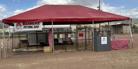 A large red tent shelters an outdoor petting zoo with metal enclosures.