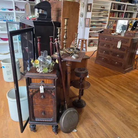 An interior shot of an antique shop filled with wooden furniture, shelves, and decorative items.