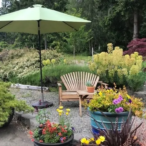 A wooden bench with an umbrella in a garden.