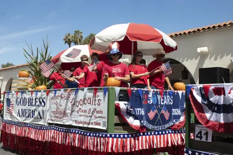 A decorated parade float with people holding American flags and pumpkins.