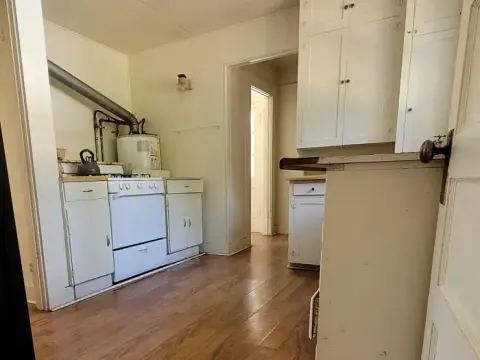 A view of the interior of a small kitchen with white cabinets and a stove.