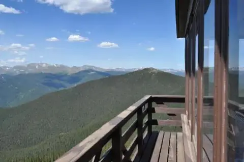 A view of mountains and forests from a lookout tower balcony.